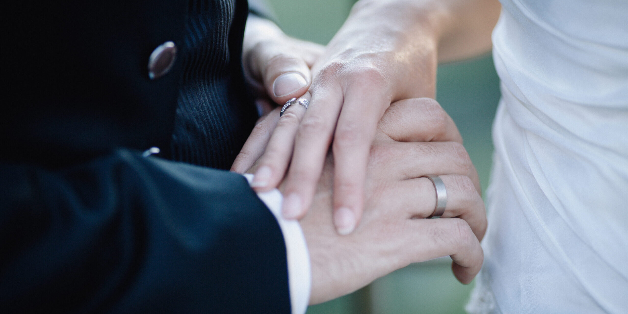 Crop married couple holding hands groom and bride holding hands with engagement rings during wedding ceremony
