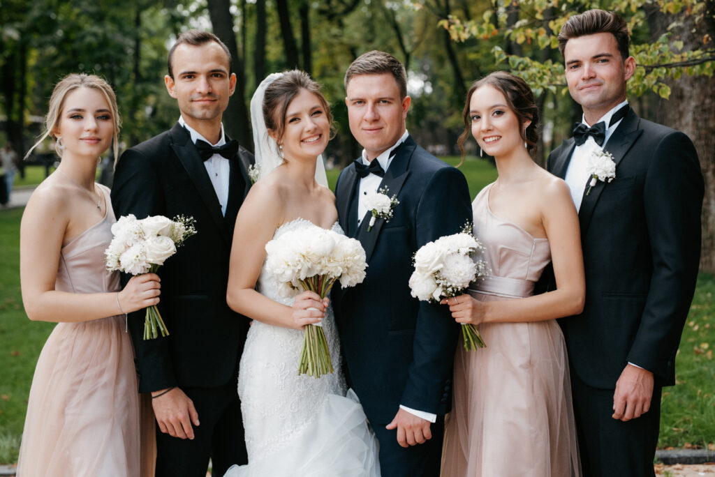 bride and groom walking with friends and girlfriends in the park on their wedding day