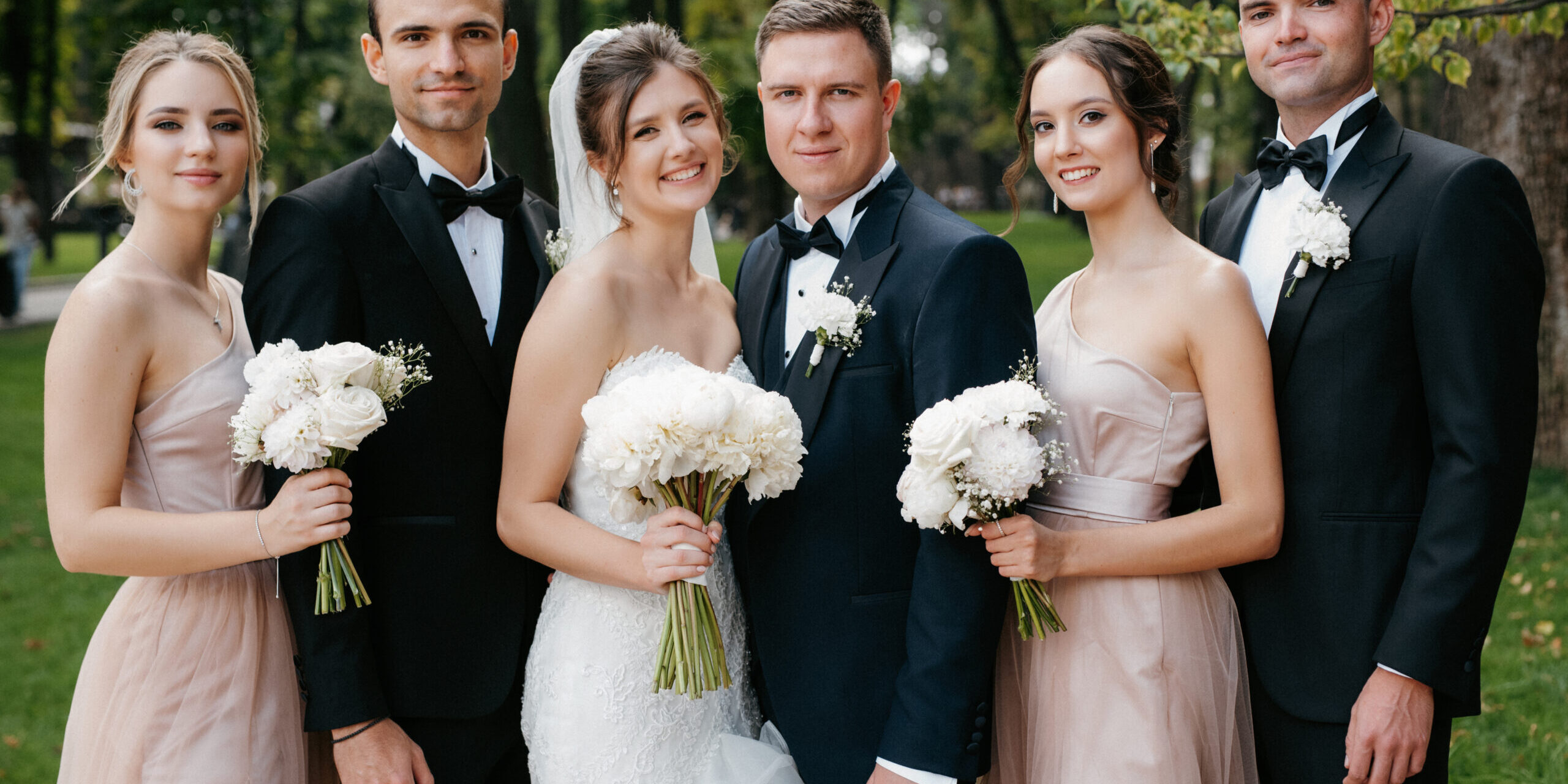 bride and groom walking with friends and girlfriends in the park on their wedding day